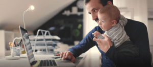Dad working on laptop while holding a baby